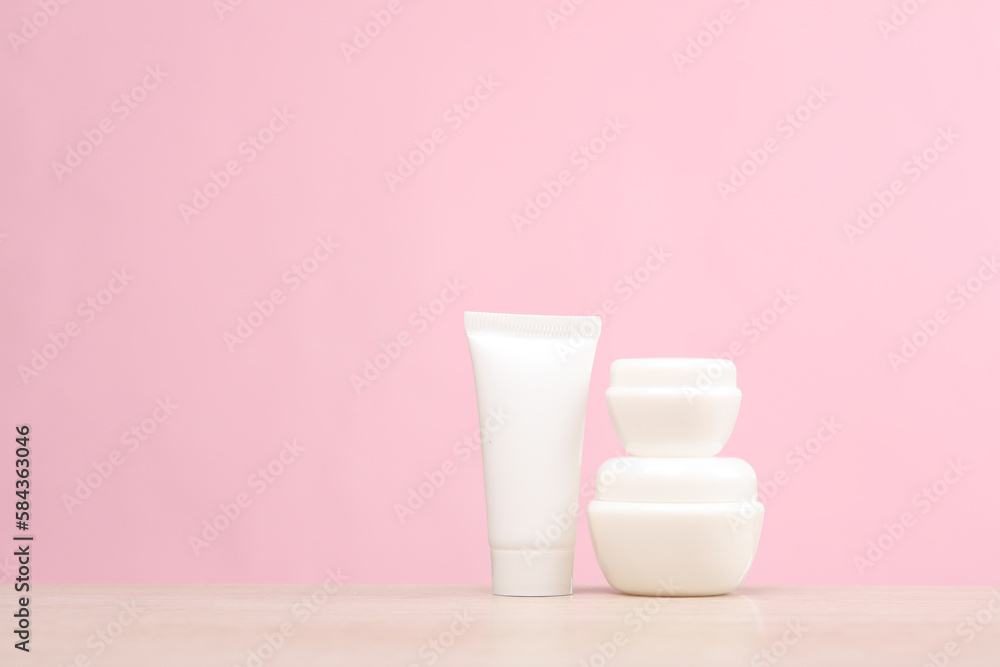 White cream tube with jars on the table, pink background. Creative layout. Template for design. Beauty mockup White cream tube with jars on the table, pink background. Creative layout. Template for design. Beauty mockup