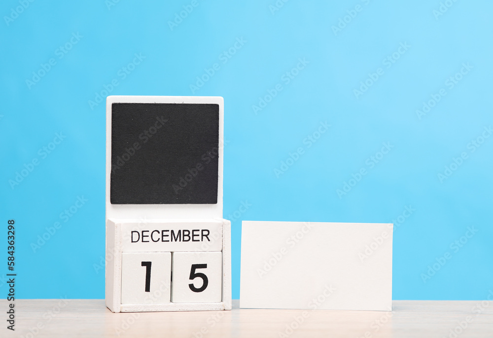 White wooden block monthly calendar with the date december 15 and business card on the table, blue background. Planning, deadline White wooden block monthly calendar with the date december 15 and business card on the table, blue background. Planning, deadline