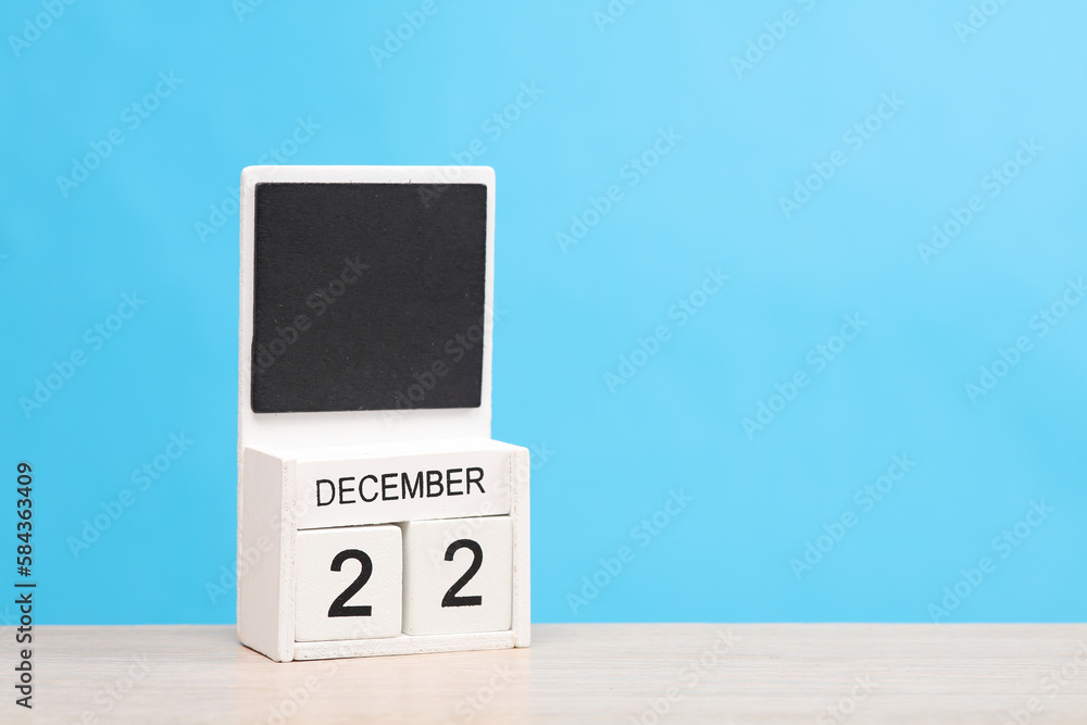 White wooden block monthly calendar with the date december 22 on the table, blue background. Planning, deadline White wooden block monthly calendar with the date december 22 on the table, blue background. Planning, deadline