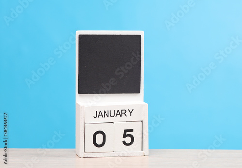White wooden block monthly calendar with the date january 05 on the table, blue background. Planning, deadline