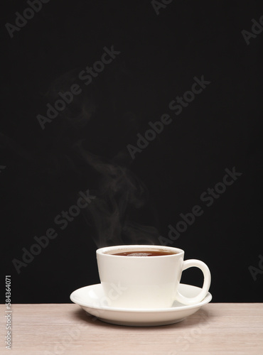 White ceramic cup with hot coffee, steam on a black background