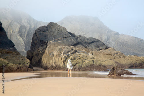 Female Figure with Sea, Cliffs and Rocks With Mist at Odeceixe Beach; Algarve; Portugal