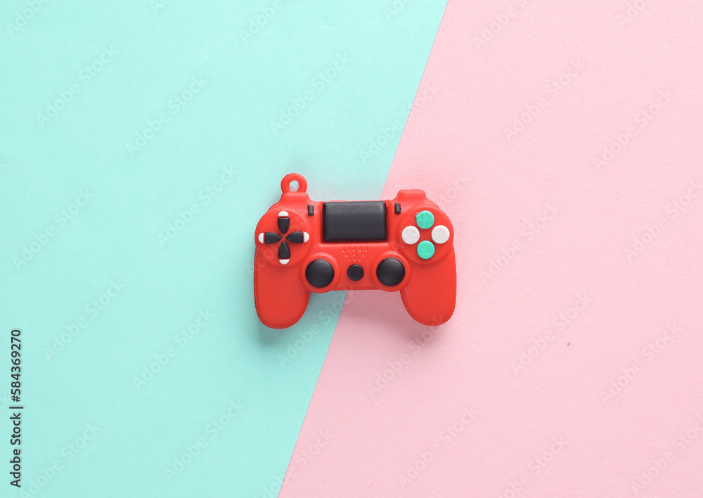 Obraz premium Red toy miniature gamepad on a pink blue background. Top view