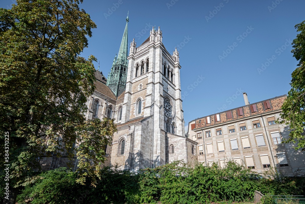 Obraz premium St Pierre Cathedral with lush green vegetation on blue sky background in Geneva, Switzerland