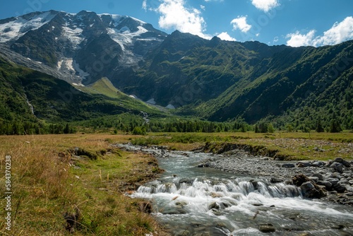 Fototapeta Naklejka Na Ścianę i Meble -  A river streaming in a middle of a green landscape in the Tour Du Mount Blanc