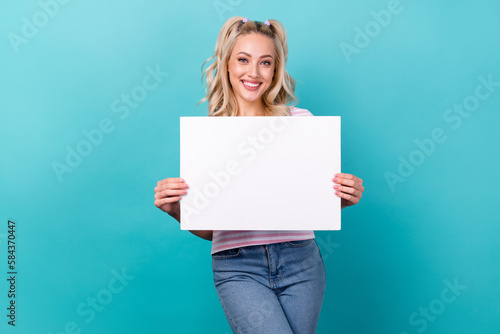 Photo of adorable youngster lady wear striped t-shirt denim jeans hold paper banner mockup new brand name isolated on aquamarine color background