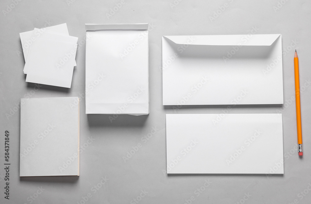 Mockup with white paper office objects. White empty envelope with a letter, lunch bag, business card, notepad and memo papers on a gray background. Template for design. Top view Mockup with white paper office objects. White empty envelope with a letter, lunch bag, business card, notepad and memo papers on a gray background. Template for design. Top view