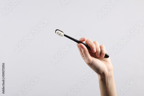 Woman's hand holds black toothbrush on a gray background. Caring for teeth concept