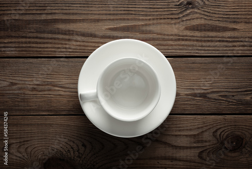Empty white ceramic cup with saucer top view on wooden table