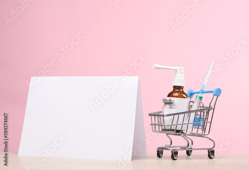 White desktop ad mockup or calendar and shopping trolley with medicines on pink background