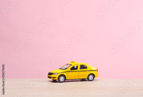 Miniature taxi car on a pink background
