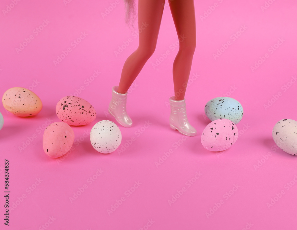 Easter minimal concept. Feet of girl doll in boots with colorful easter eggs on yellow background
