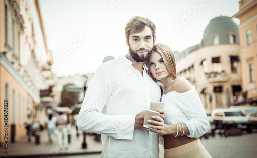 Young couple in love drinking coffee on the go in city