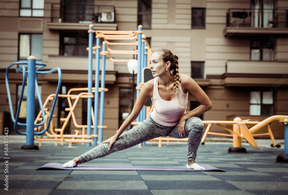 Fit woman practicing leg stretching on the outdoor playground. Active lifestyle