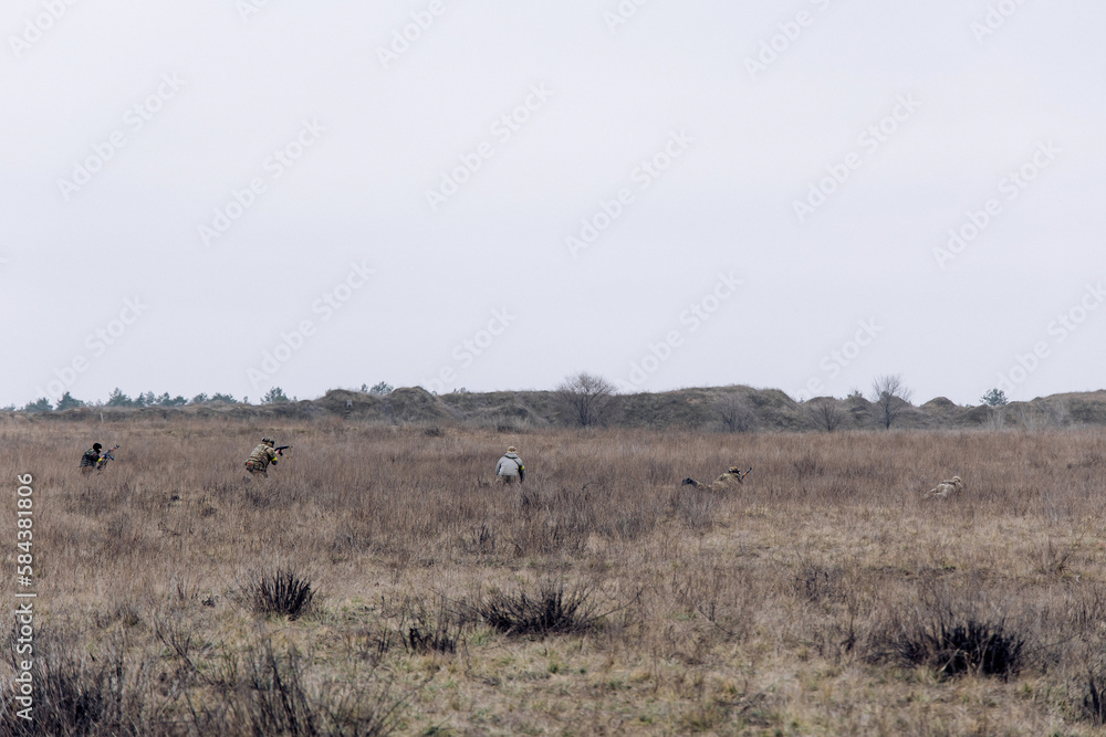 Group of armed Ukrainian soldiers attacks of enemy in steppe.