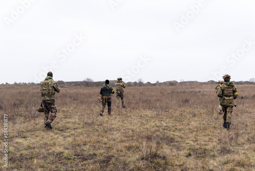 Group of armed Ukrainian soldiers walks through steppe. © Stanislav