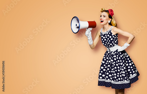 Portrait image of beautiful woman holding mega phone, shout advertising. Pretty girl in black pin up dress, white glows with megaphone loudspeaker. Isolated latte beige background. Big sales ad.