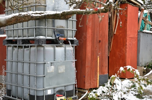 Rainy water flowing from a plastic container in the garden before frozen winter
