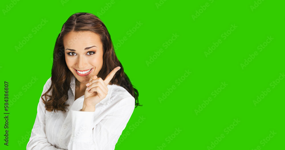 Young happy smiling woman in confident blouse, showing pointing finger aside at copy space area. Business ad concept. Brunette businesswoman, green chroma key background. Young happy smiling woman in confident blouse, showing pointing finger aside at copy space area. Business ad concept. Brunette businesswoman, green chroma key background.