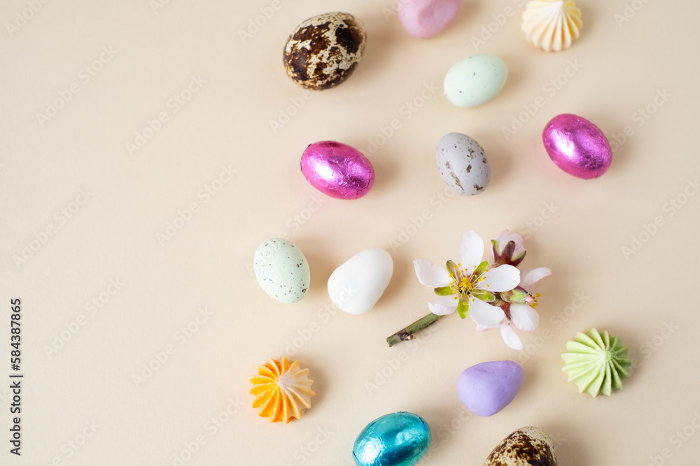 Easter chocolate and decorative eggs and spring flowers on a beige background