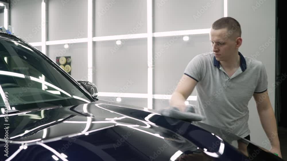 The worker wipes the car with a rag. Car service worker applying nano coating on a car detail. Car detailing concept. Vehicle detailing. The worker wipes the car with a rag. Car service worker applying nano coating on a car detail. Car detailing concept. Vehicle detailing.