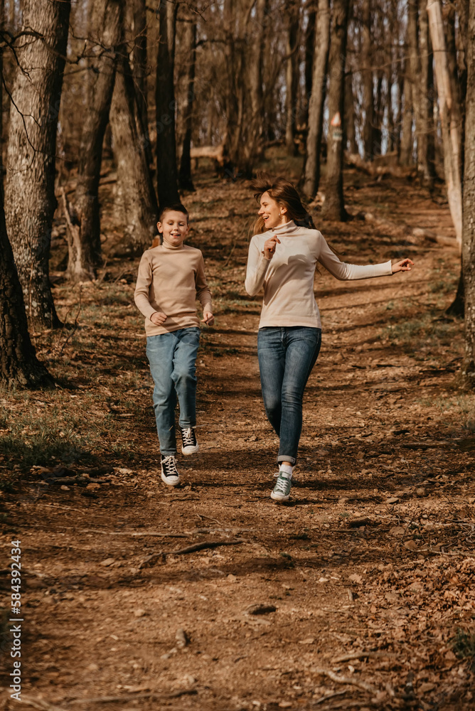 Happy Mother and Child Running on Path in Forest Happy Mother and Child Running on Path in Forest