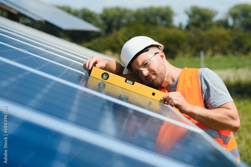 Male engineer in protective helmet installing solar photovoltaic panel system. Alternative energy ecological concept. Male engineer in protective helmet installing solar photovoltaic panel system. Alternative energy ecological concept.