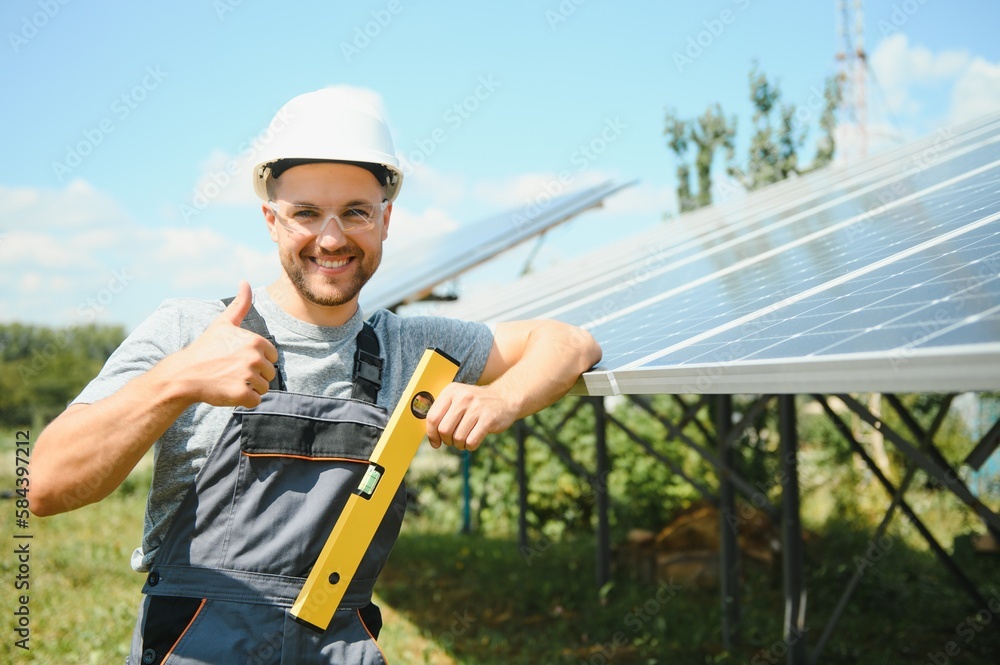 Male worker with solar batteries. Man in a protective helmet. Installing stand-alone solar panel system Male worker with solar batteries. Man in a protective helmet. Installing stand-alone solar panel system