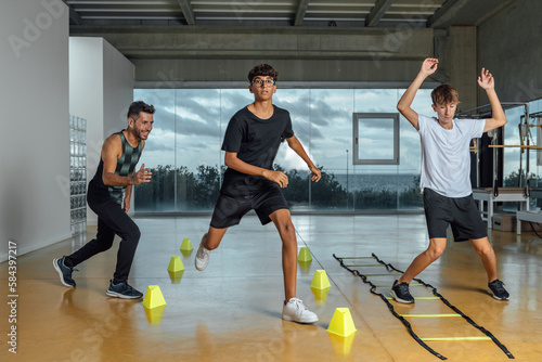 Fotografie Teenagers and instructor performing circuit routine functional training at the gym