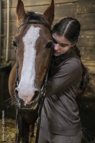 A girl jockey hugs her horse after a riding lesson. Vertical image.
