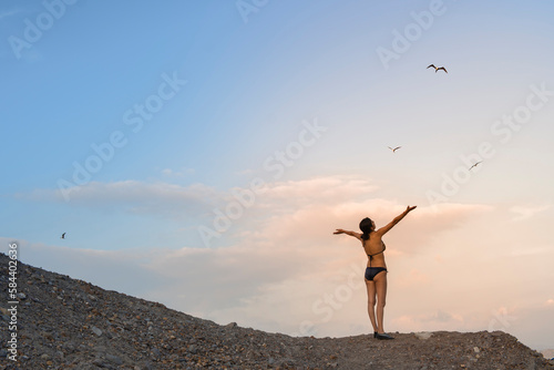woman raising her arms in a sunset beach landscape enjoying her vacation.