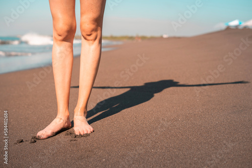 woman legs close up on the beach reflecting her shadow stretching out her arms at sunset.