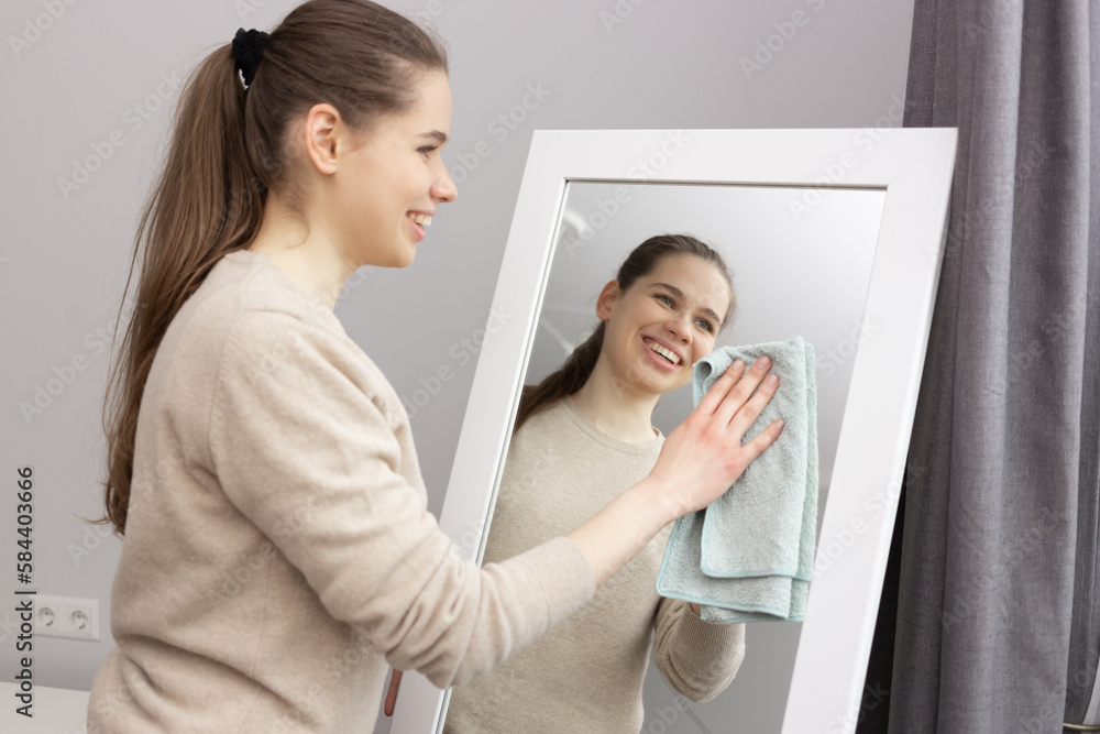 A girl is wiping the dust off the mirror