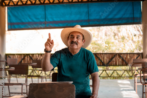 An older adult raises his hand to give his opinion in a classroom in the middle of the jungle
