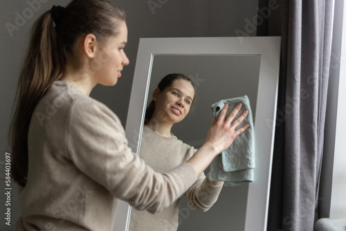 Tablou pe pânză A girl is wiping the dust off the mirror