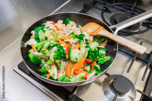 Stir fry vegetables cooking in a stainless steel pan.