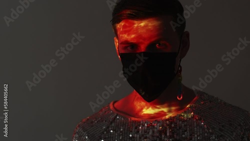 Stylish look. Lgbtq male portrait. Safety desiase. Gay man in spangle shirt black protective mask posing gray background with double exposure sunset light overlay reflection lens flare. photo