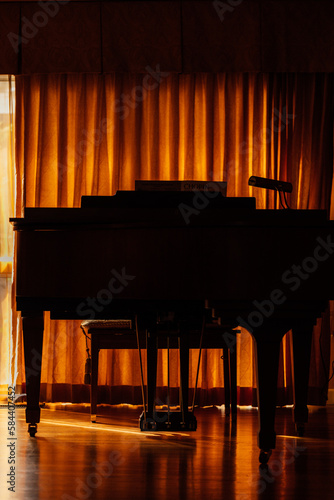 silhouette of baby grand piano with golden curtains