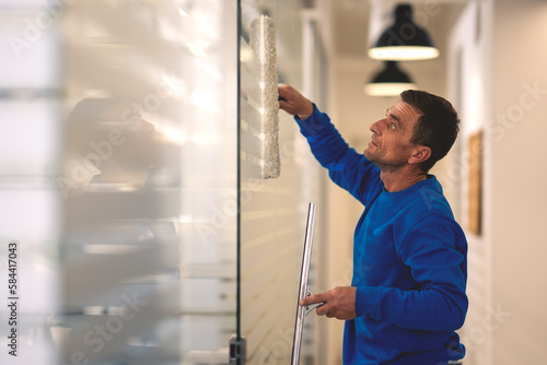 Cleaner cleans the glass panels in the office