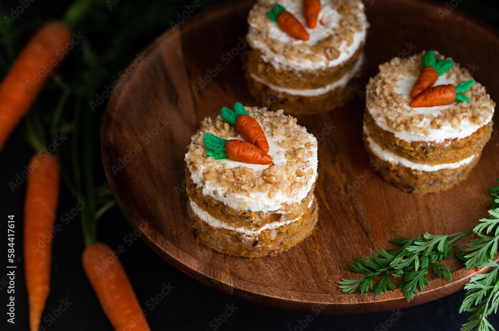Easter Carrot cake Rüeblitorte with cream cheese frosting and marzipan decorations on a wood plate for festive dinner. Small easter bento cake. Fresh homemade carrot cake. Traditional Easter food. Easter Carrot cake Rüeblitorte with cream cheese frosting and marzipan decorations on a wood plate for festive dinner. Small easter bento cake. Fresh homemade carrot cake. Traditional Easter food.