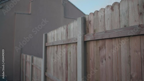 Garden fence walking along wooden dividing fence between houses slow motion tracking shot