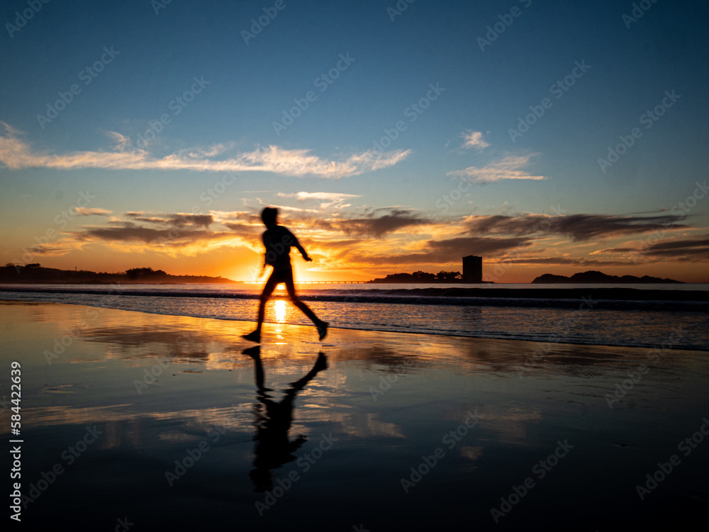 Silueta de una mujer en la playa a la puesta de sol