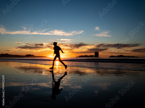 Silueta de una mujer en la playa a la puesta de sol © Incongo Art