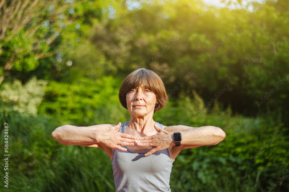 An old slender woman does yoga in the park