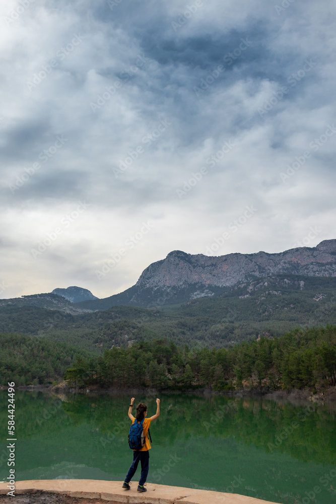 happy child rejoices at the mountain lake..A child with a backpack looks at a beautiful mountain lake. happy child rejoices at the mountain lake..A child with a backpack looks at a beautiful mountain lake.