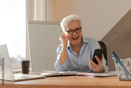 Obraz na plátne Confident middle aged senior woman euphoric winner with smartphone