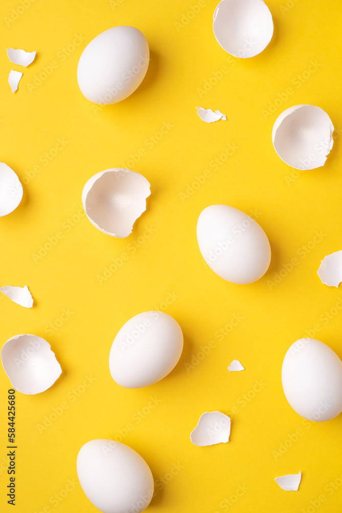 Minimalistic Easter background. White Easter eggs and shells on a bright yellow background. Top view.
