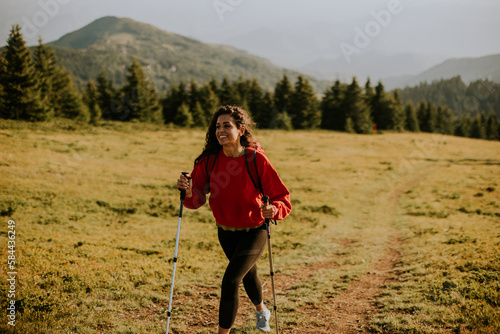 Young woman walking with backpack over green hills
