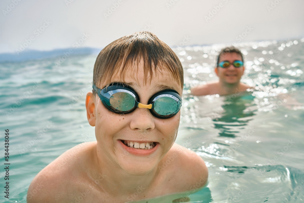 Happy family in swimming goggles, father and son bonding, play, swim in the sea looking at view enjoying summer vacation. Togetherness Friendly concept
