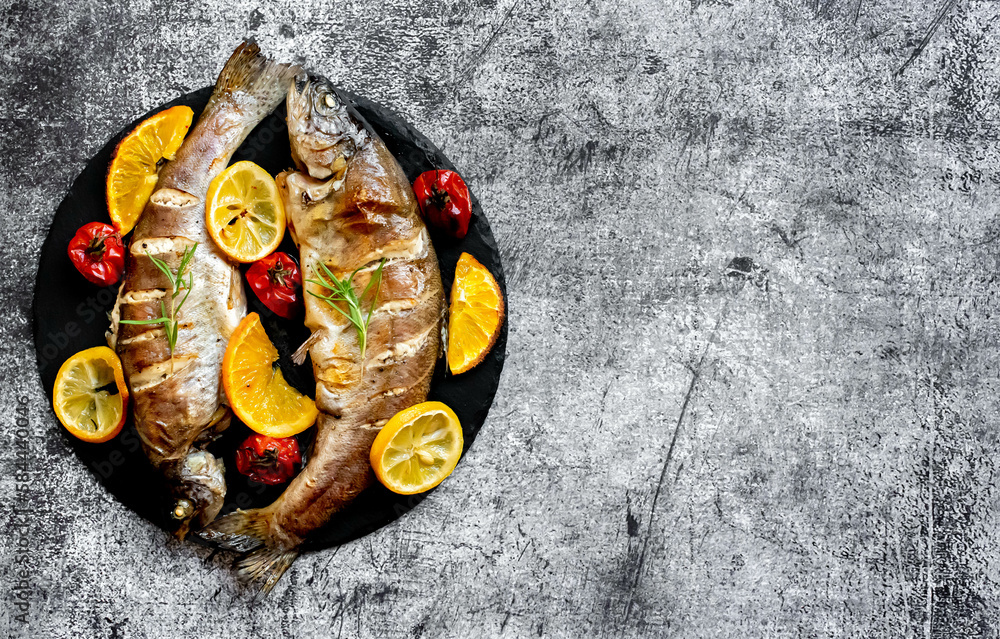 baked trout with lemon, orange, spices on a stone background with copy space for your text